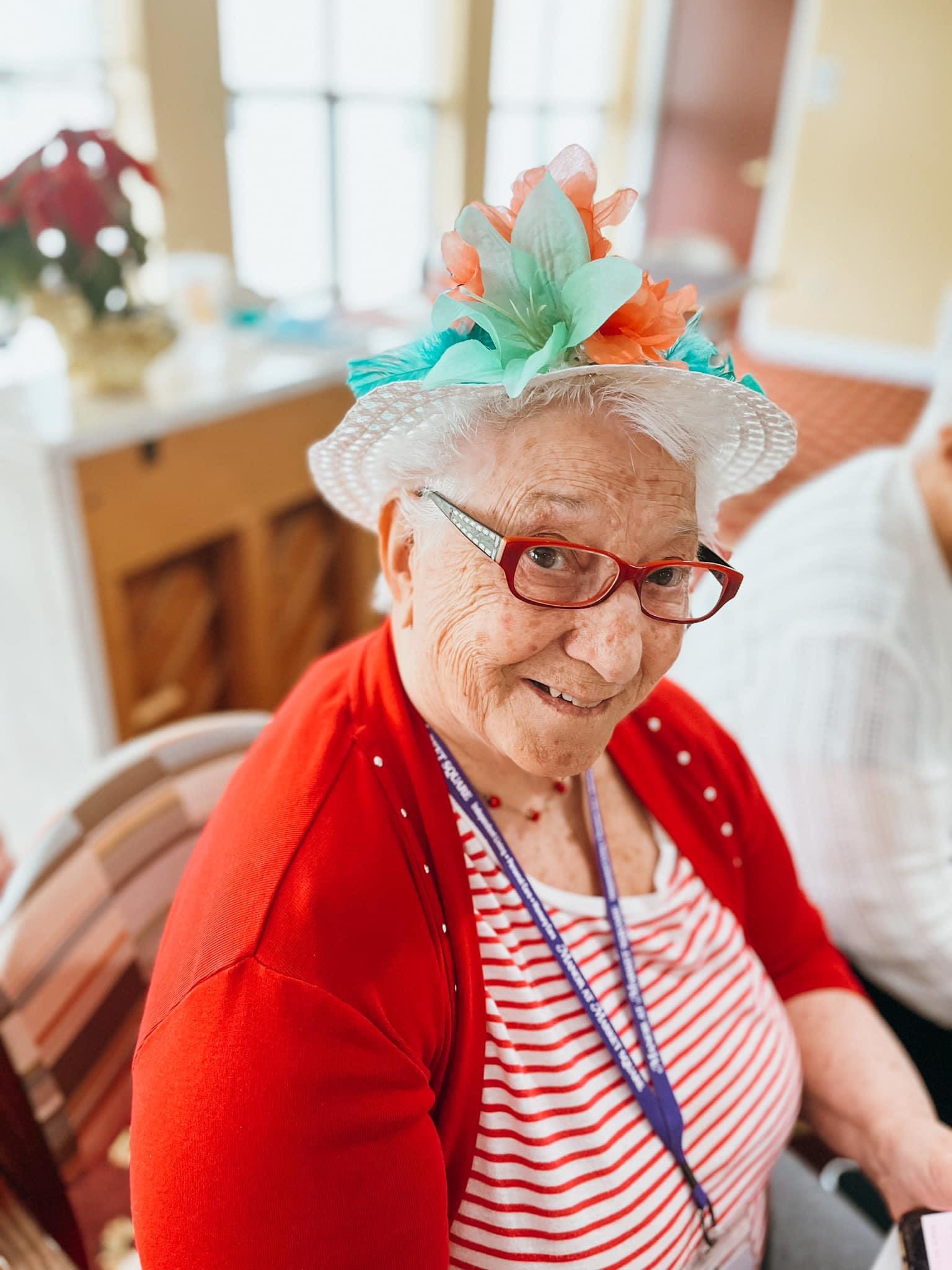 Smiling elderly woman wearing floral hat indoors